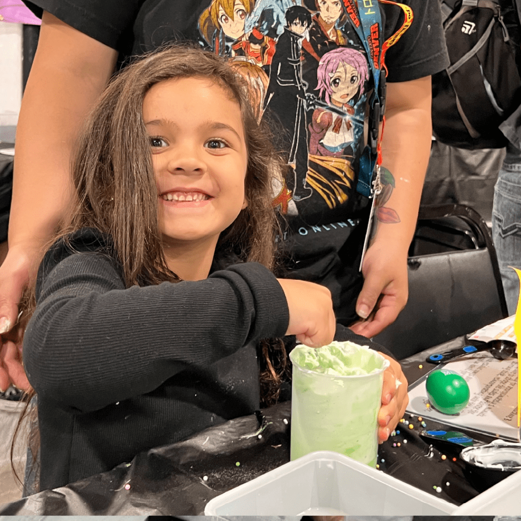 A child smiles as she works on an activity in the 2021 Alien Slime Lab